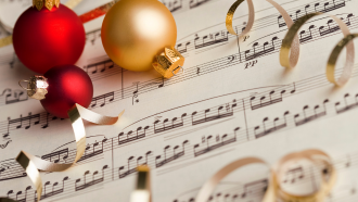 red and gold baubles sitting atop sheet music